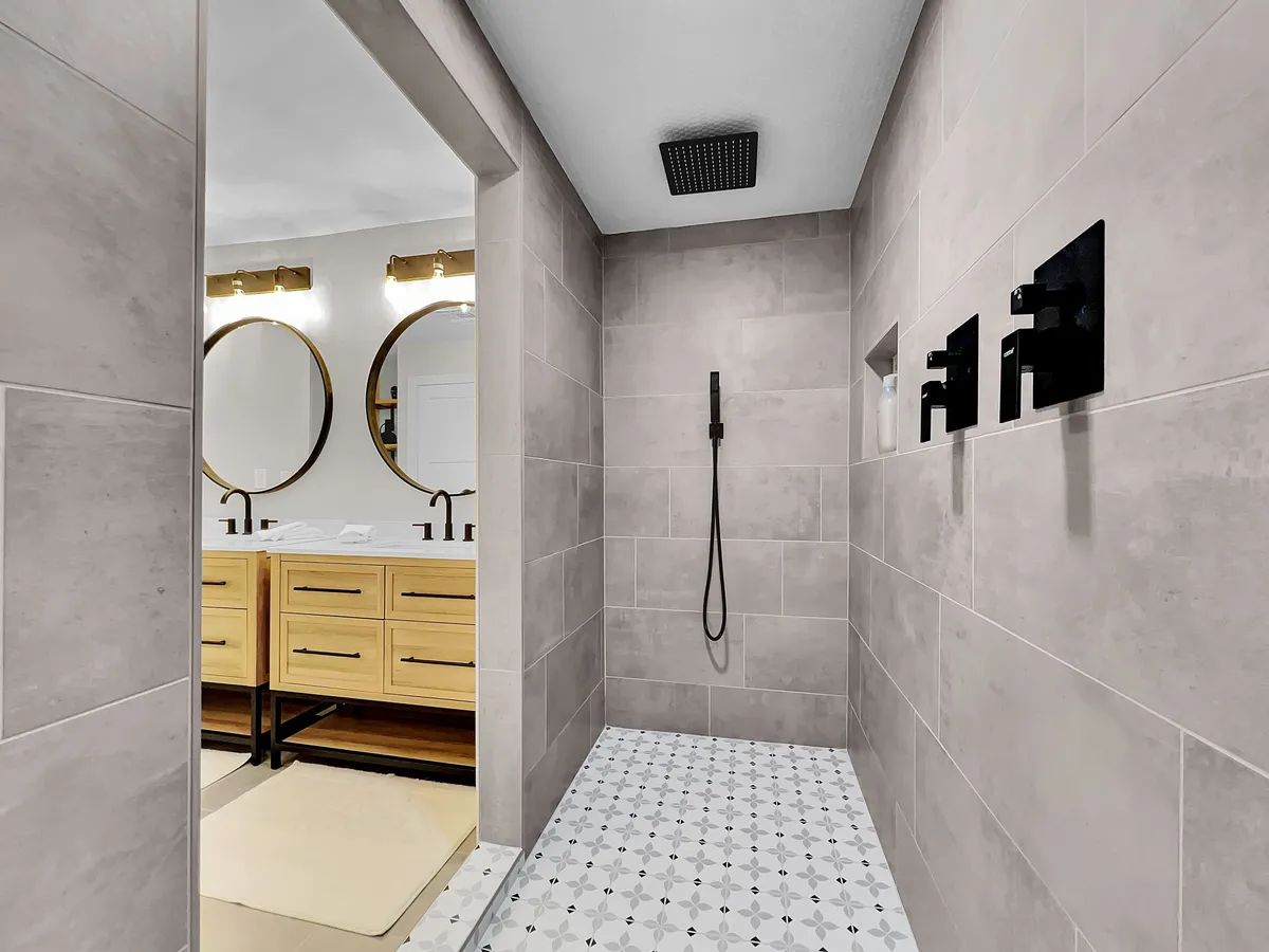 A spa-inspired bathroom featuring a spacious walk-in shower area, dual vanity mirrors, and elegant wooden cabinetry. The design exudes a sense of relaxation and indulgence, perfect for unwinding after a day of exploration.