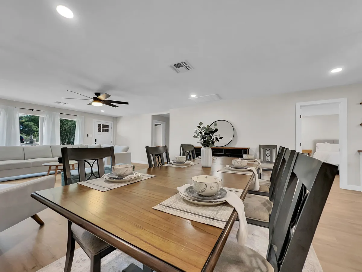 A cozy dining area with a large table suitable for family meals or board games, a decorative vase as the centerpiece, and a comfortable sofa area in view. The arrangement suggests a space ideal for group dining, celebrating special occasions, and relaxing together after a day of exploring the city.